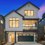 three story white house with black trim taken at night so the windows are illuminated
