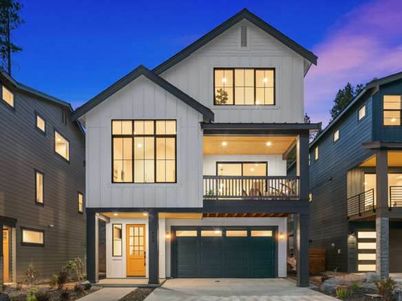 three story white house with black trim taken at night so the windows are illuminated