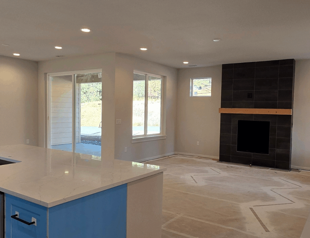 Ederra homesite 21 living room with fireplace and kitchen island view while under construction