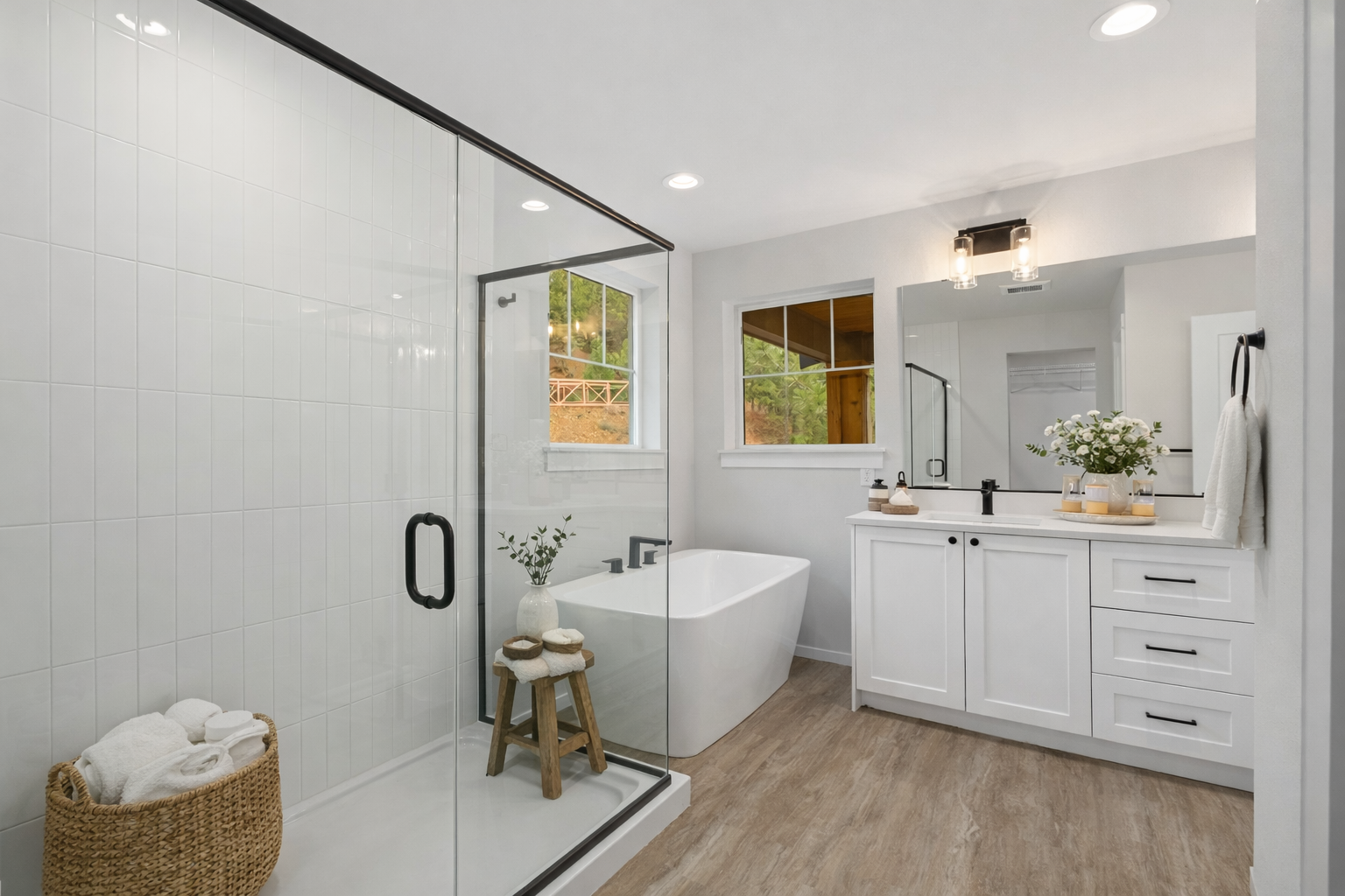 The Thorp at Ederra in Cle Elum by Trailside Homes virtually staged primary suite bathroom with white soaking tub, large, tiled walk-in shower, and sink with white cabinets and black faucets and hardware