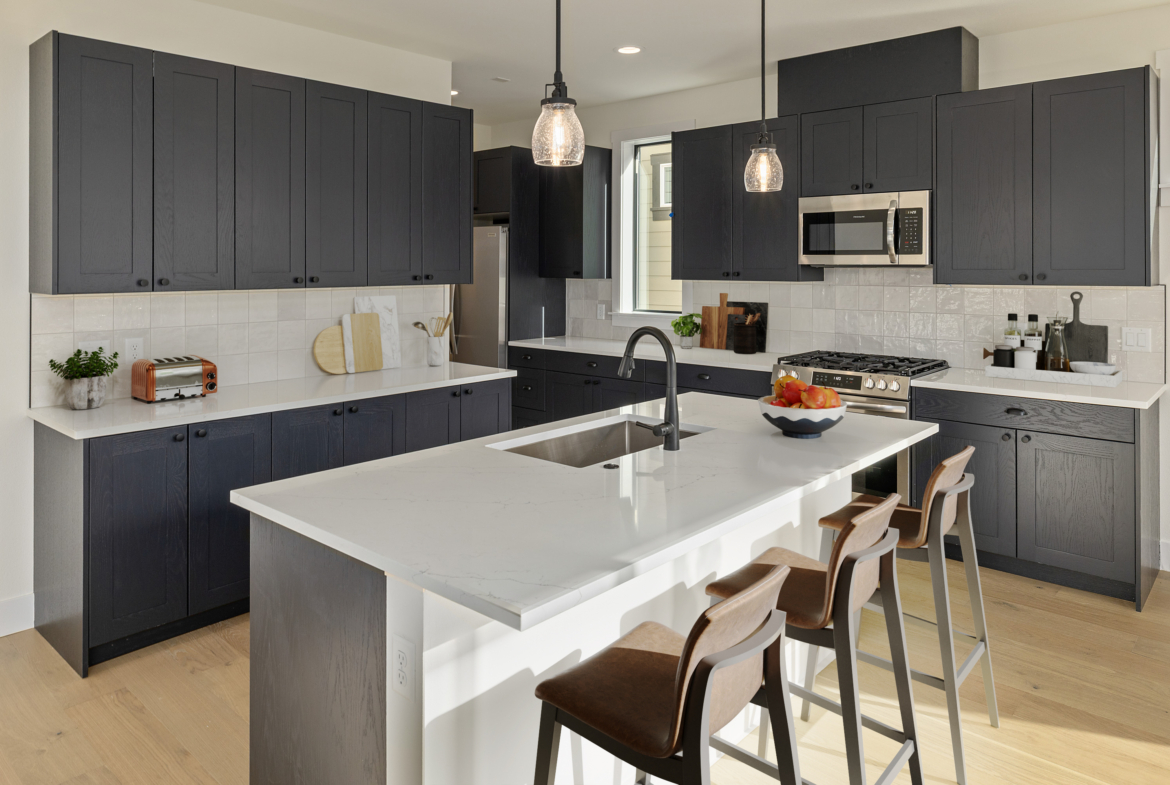 The Naches Ederra 7 kitchen with dark cabinets and chairs up to the island overhang