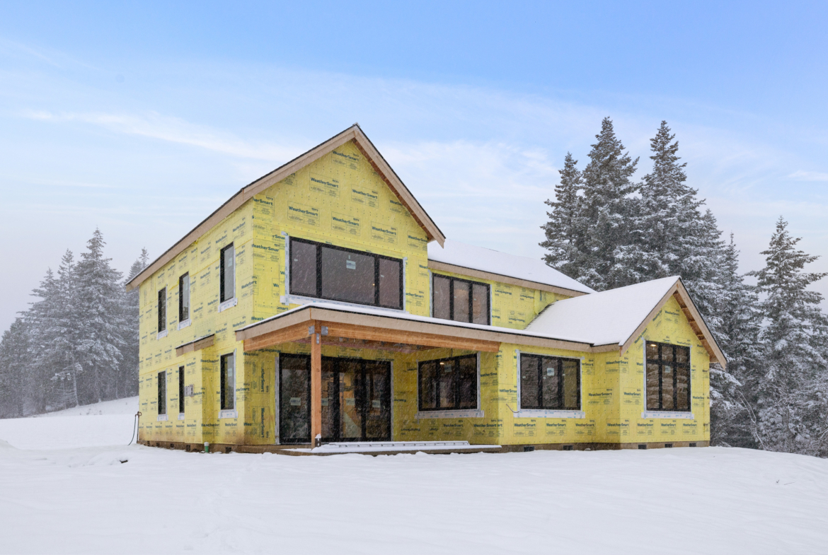 Skyline Ridge homesite 55 progress photo back exterior with covered patio and covered in snow